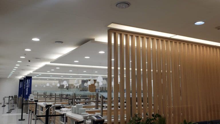 Forro de gesso comercial com iluminação embutida e divisória de madeira em ambiente corporativo